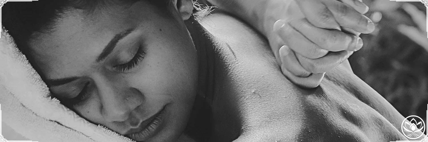 Femme allongee sur le ventre, visage apaise sur serviette douce, main du praticien massant le dos pour une detente profonde.